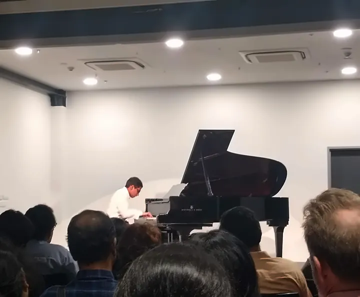 A student performing on a grand piano for an audience